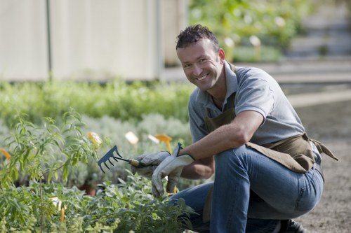 Gardener wearing PPE using powered hedge trimmer